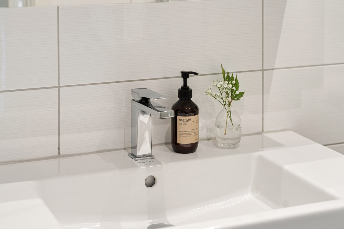 Un lavabo blanco y limpio con azulejos y objetos cotidianos sencillos