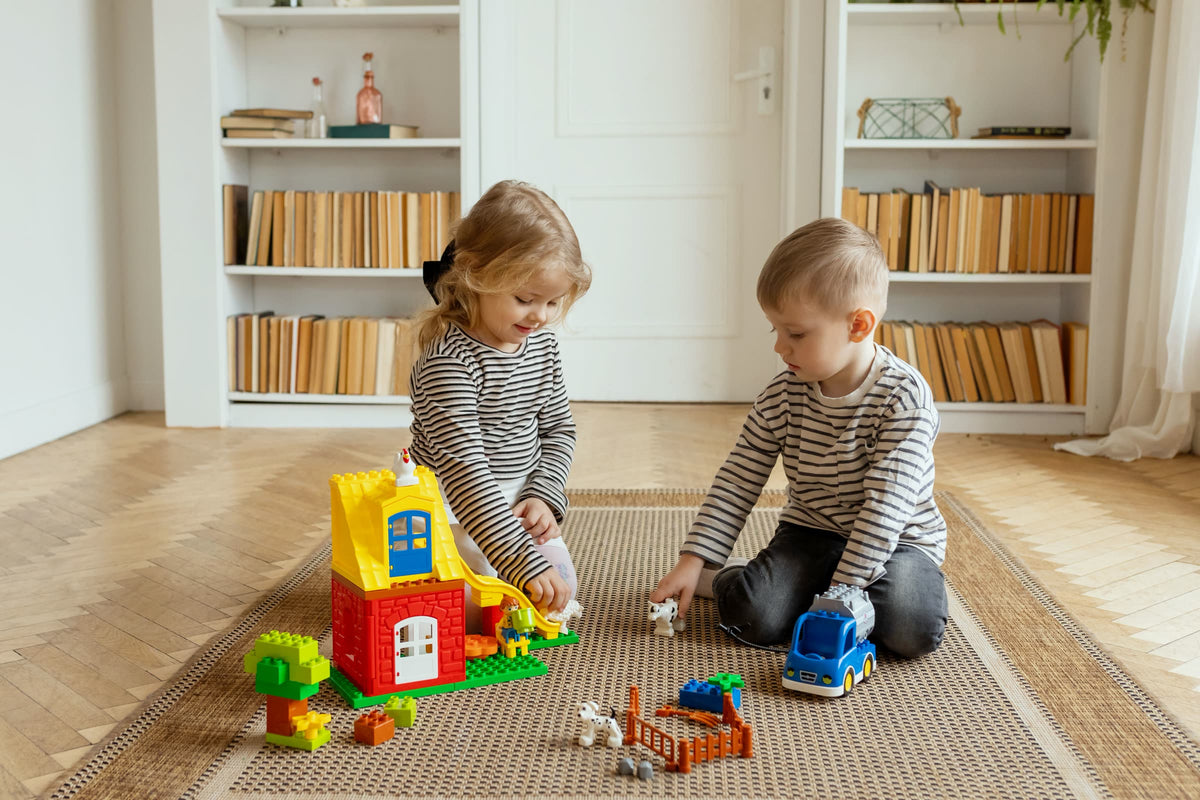 Zwei Kinder spielen gemeinsam mit Spielzeug in einem hellen Wohnzimmer