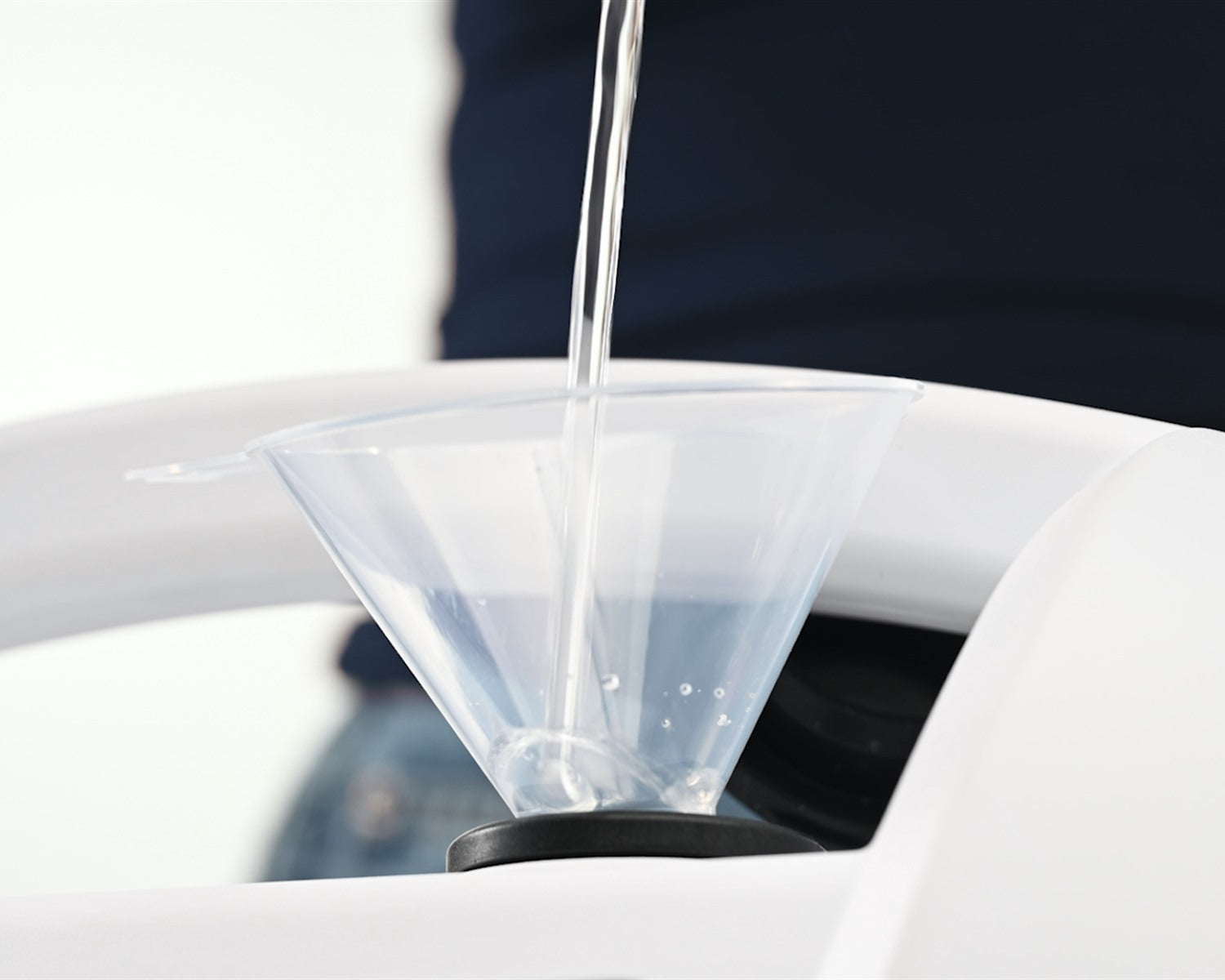 Vertido de agua por el embudo de recarga de un limpiador de vapor Pearl White